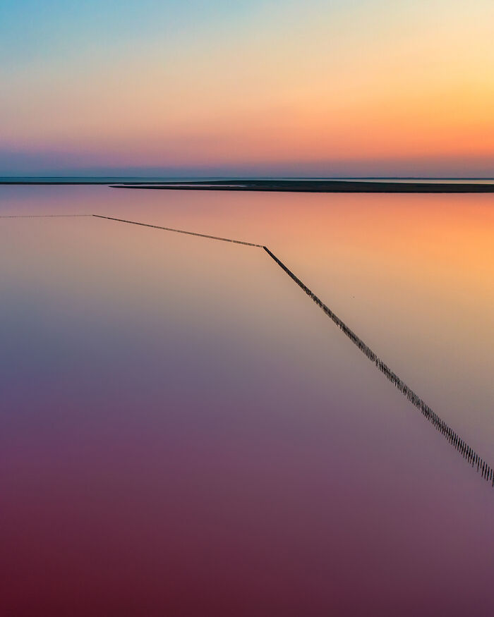 Aerial image of calm water with colorful sunset hues and geometric lines showcasing the world from a new perspective.