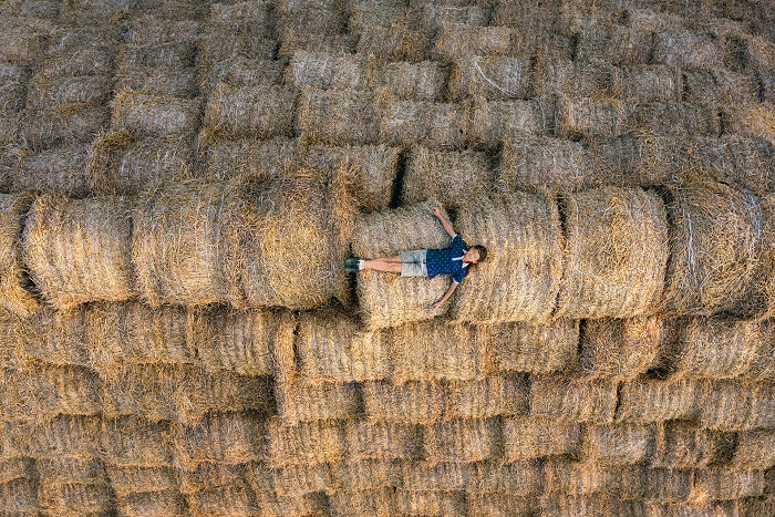 Aerial image of a person lying on stacked hay bales showcasing the world from a new perspective.