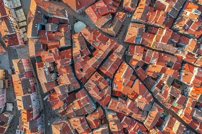 Aerial image capturing a dense, historic cityscape with red rooftops, showcasing the world from a new perspective.
