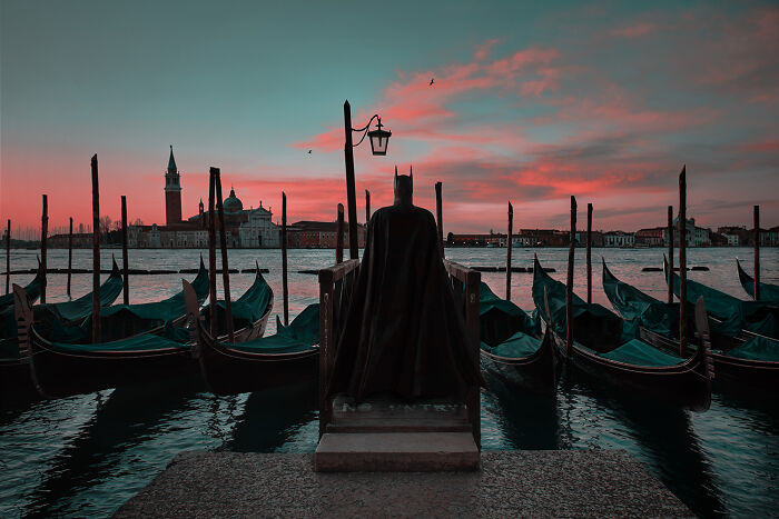 Batman overlooking gondolas at sunset, blending into daily life by the canal.