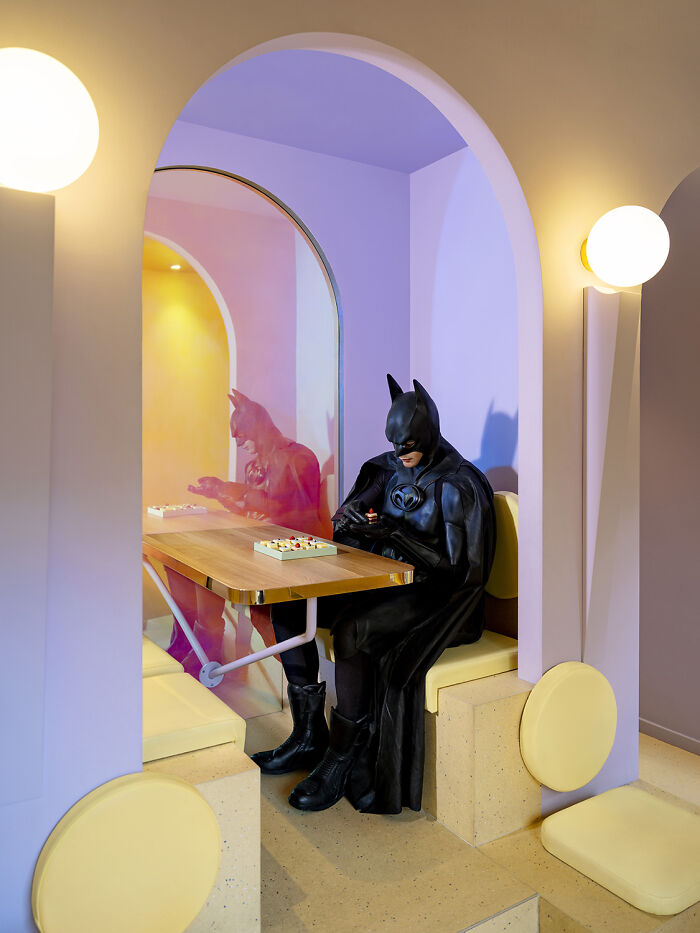 Batman enjoying a quiet moment at a cafe, captured by an artist in a playful setting.