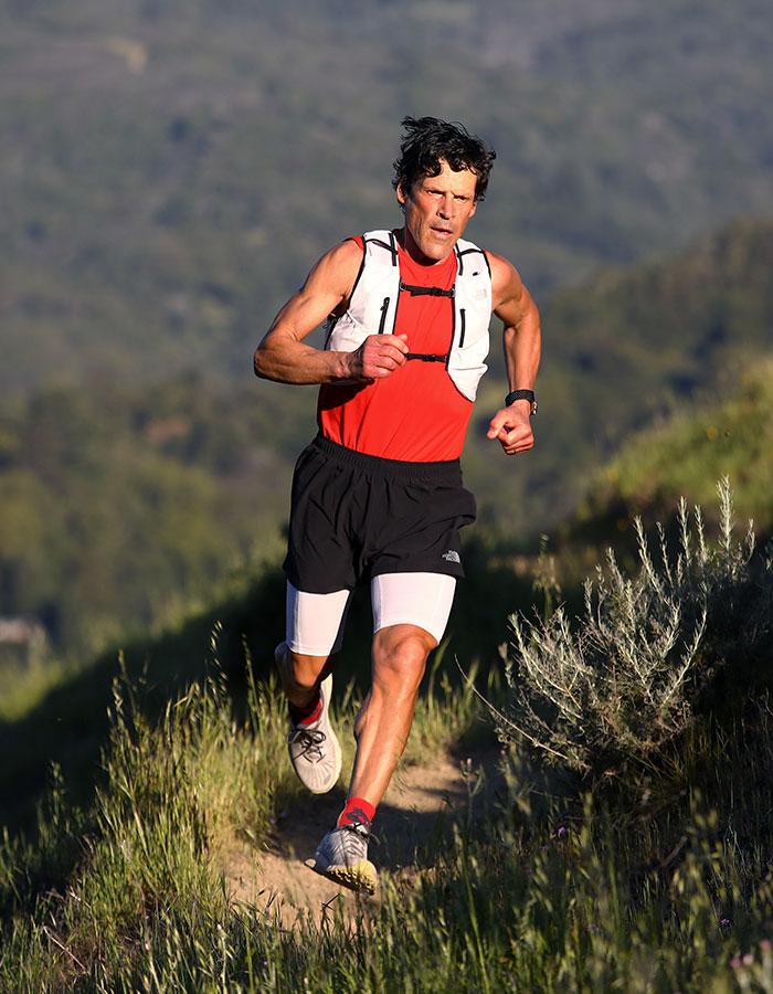 Runner showcasing real-life superpowers, wearing a red and white outfit, on a trail surrounded by greenery.