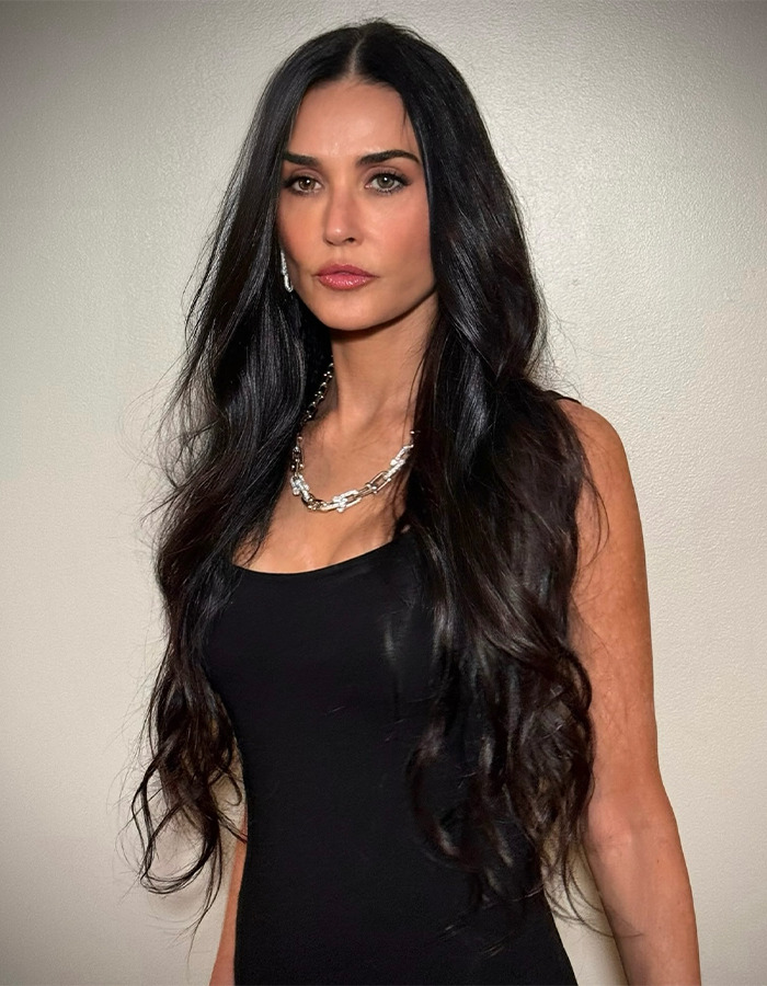 A woman with long dark hair in a black dress, wearing a silver necklace, showcasing natural beauty. A woman with long dark hair in a black dress, wearing a silver necklace, showcasing natural beauty.