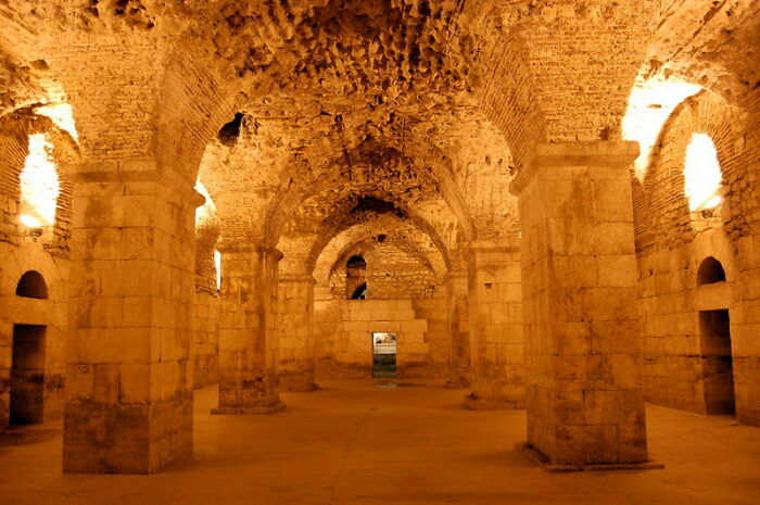 Underground city with stone columns and arches, dimly lit, showcasing eerie architecture.