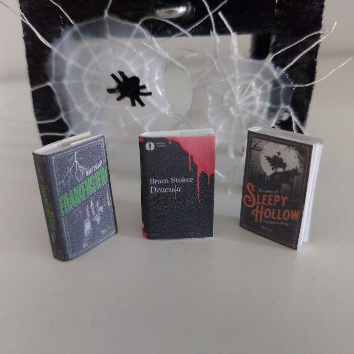 Miniature books of Frankenstein, Dracula, and Sleepy Hollow in front of a spider web, creating a secret world.