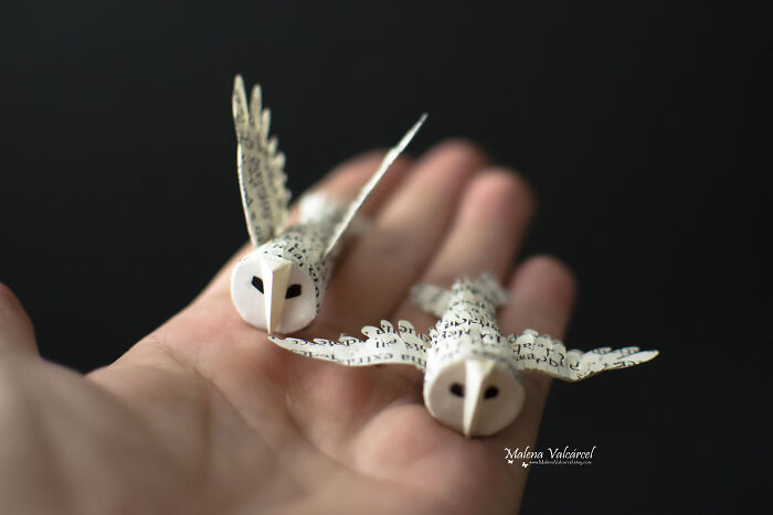 Hand holding intricate miniatures of owls crafted from paper with lettering, showcasing exquisite details.