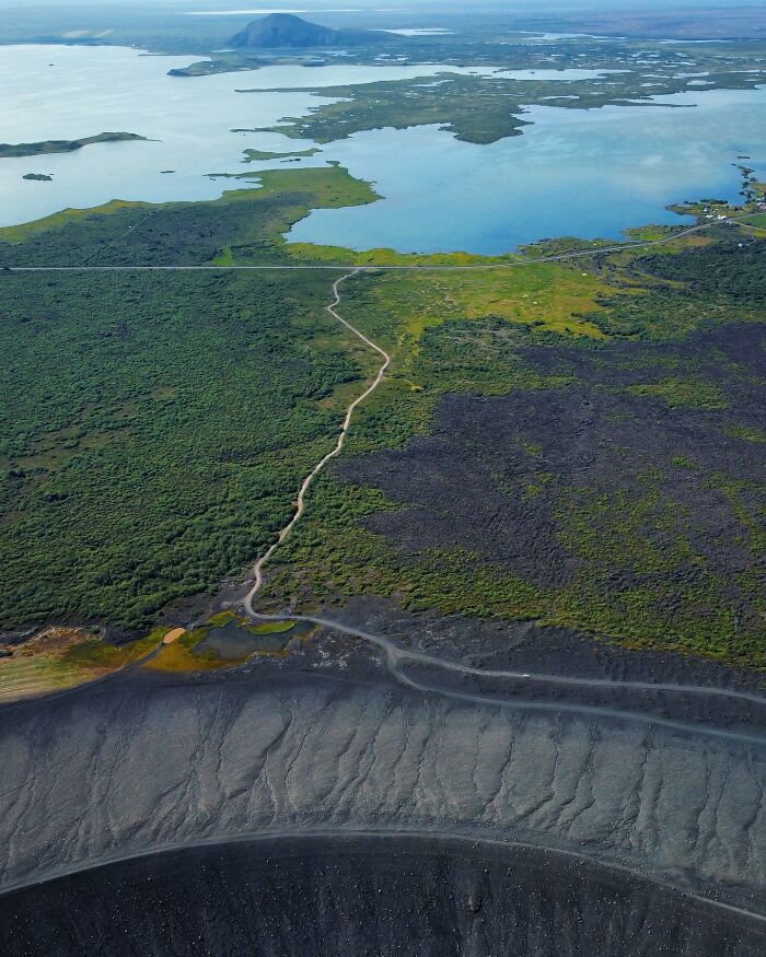 Drone photograph by Dimitar Karanikolov capturing a diverse landscape with a winding road and serene lake.