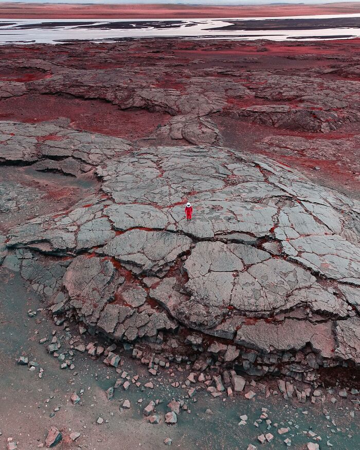 Drone photograph by Dimitar Karanikolov showing a solitary figure in red on a vast rocky landscape.