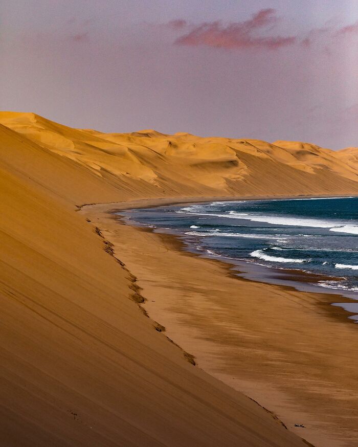 Aerial view of a stunning beach with sand dunes meeting the ocean, captured by Dimitar Karanikolov's drone photography.
