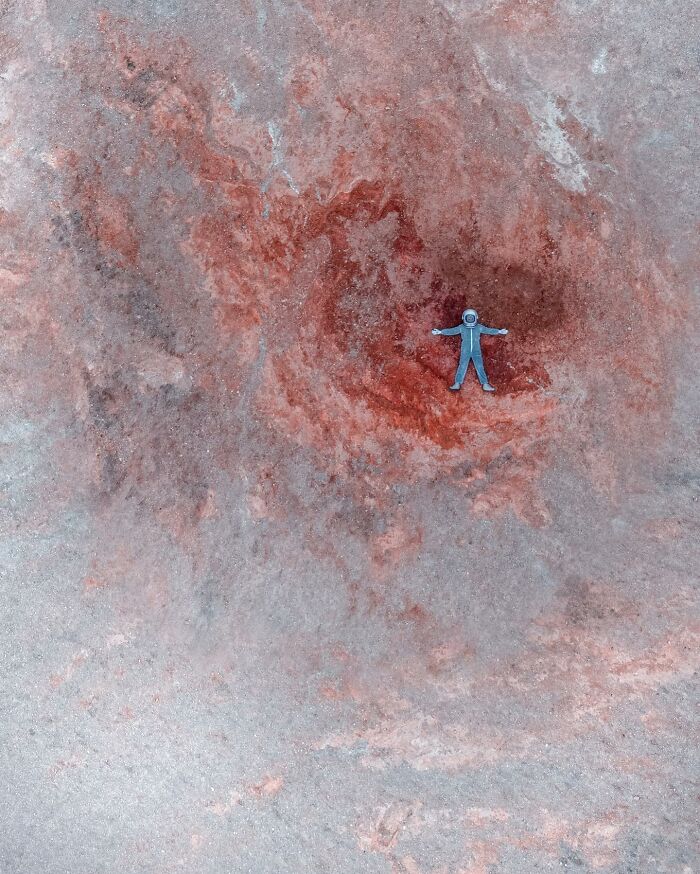 Aerial view of a blue figure on a reddish-brown terrain, captured by drone photograph.