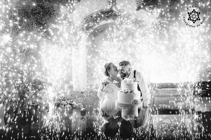 Bride and groom sharing a moment by the wedding cake, surrounded by sparkling lights at the Premios FDB Awards.