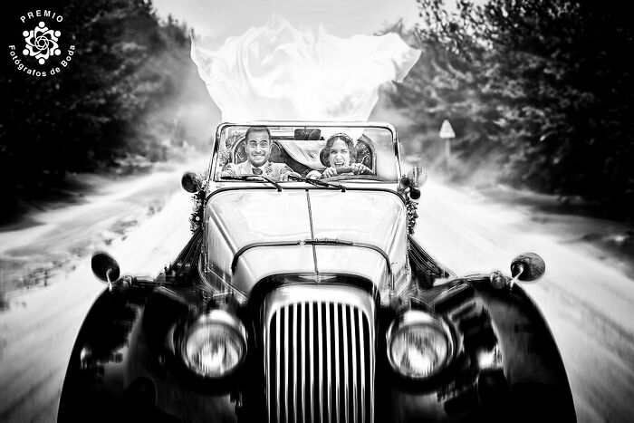 A joyful couple in a classic car, capturing a dynamic black and white wedding photo from the 2025 Premios FDB Awards.