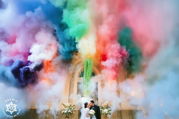Couple kissing under vibrant colored smoke at award-winning wedding, Premios FDB 2025.