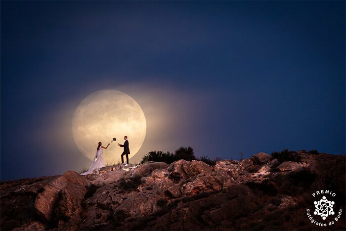 Bride and groom pose against a full moon on rocky terrain, capturing a stunning wedding photo from the 2025 Premios FDB Awards.
