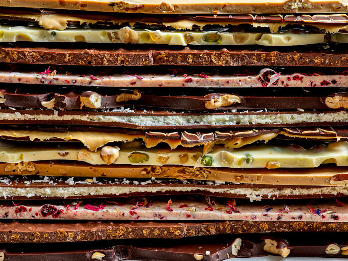 Stacked layers of artisanal chocolate bars, featuring nuts and dried fruits, highlighted in World Food Photography Awards.
