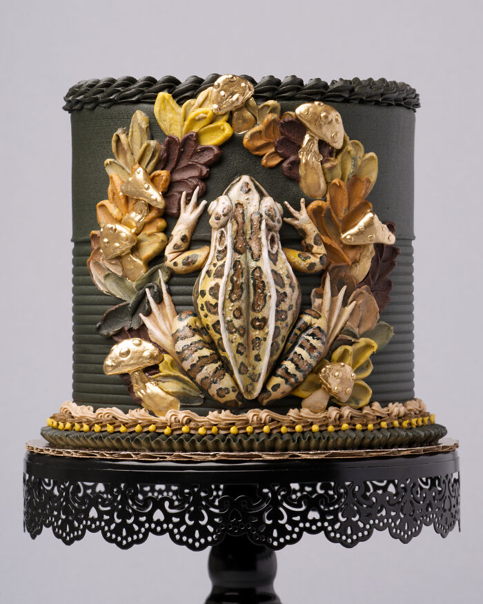 Vegan cake decorated with a detailed frog, surrounded by edible leaves and mushrooms.