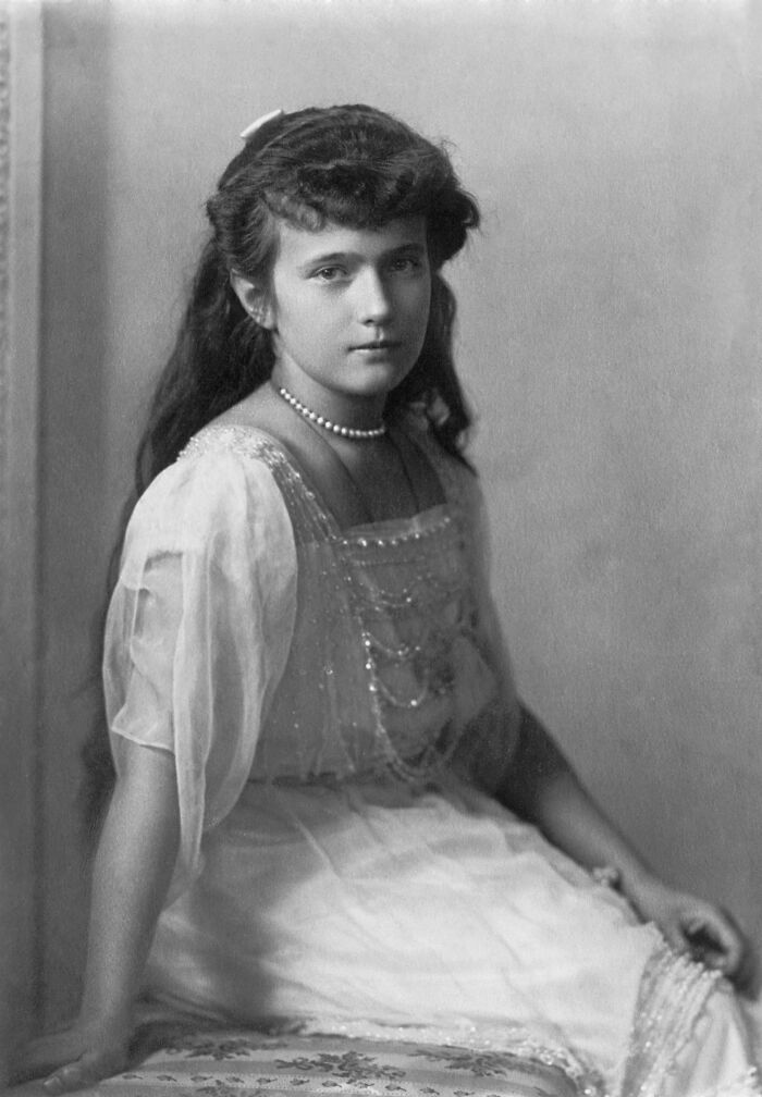 Young woman in vintage dress with pearl necklace in a rare photo of famous historical figures from early 20th century.