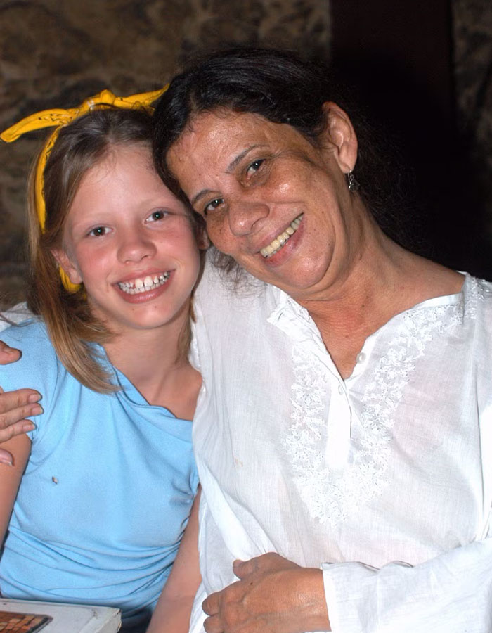 Grandmother of actress smiling with young girl, both embracing and looking at the camera.