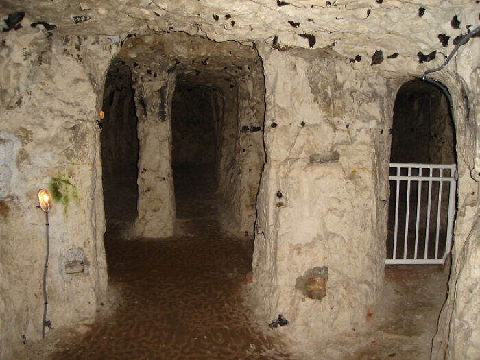Underground city passage with stone walls and gated entrance.