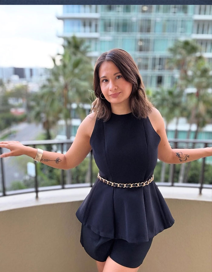 Woman in black dress with tattoos, showing weight loss transformation on a balcony with city backdrop. Woman in black dress with tattoos, showing weight loss transformation on a balcony with city backdrop.