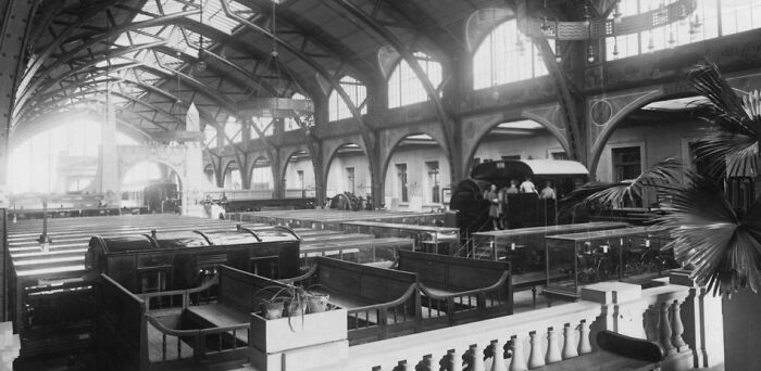 Historic black and white photo showing life in Europe 100 years ago inside a large, vaulted train station.
