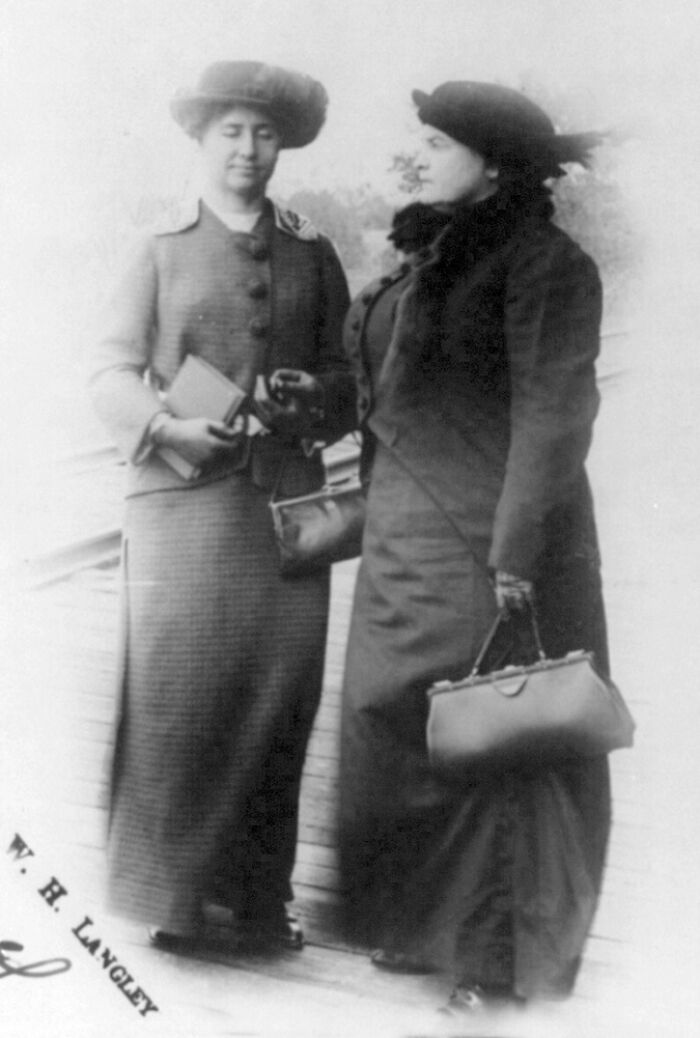 Two women dressed in early 20th-century attire standing outdoors in a rare photo of famous historical figures