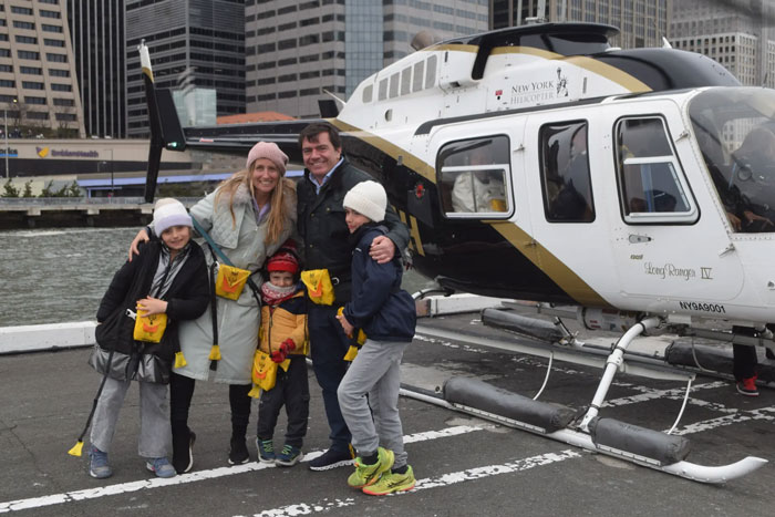 Family posing with helicopter near Hudson River, New York.