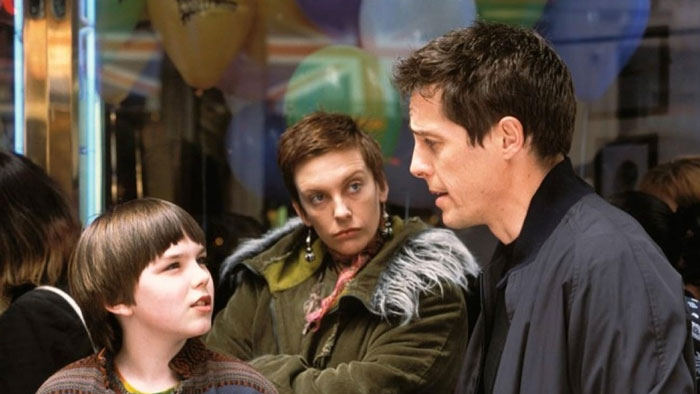 A man in a dark jacket speaks to two others, expressing concern about elite school rules. A man in a dark jacket speaks to two others, expressing concern about elite school rules.