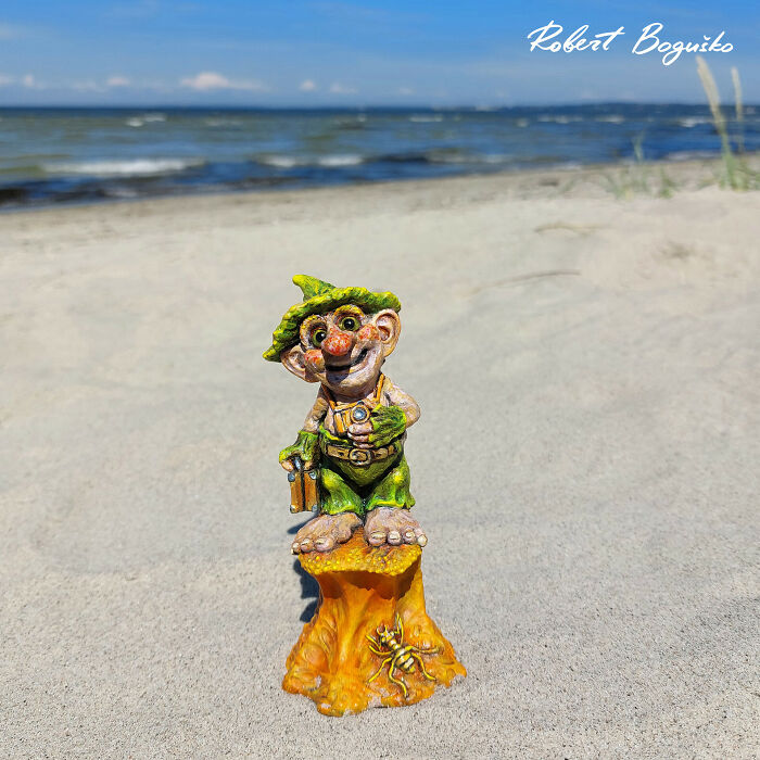 Whimsical troll sculpture crafted from outdoor materials, set against a sandy beach backdrop.