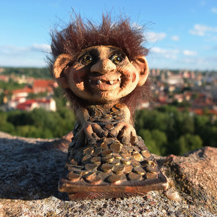 Whimsical outdoor troll sculpture with a cityscape backdrop.