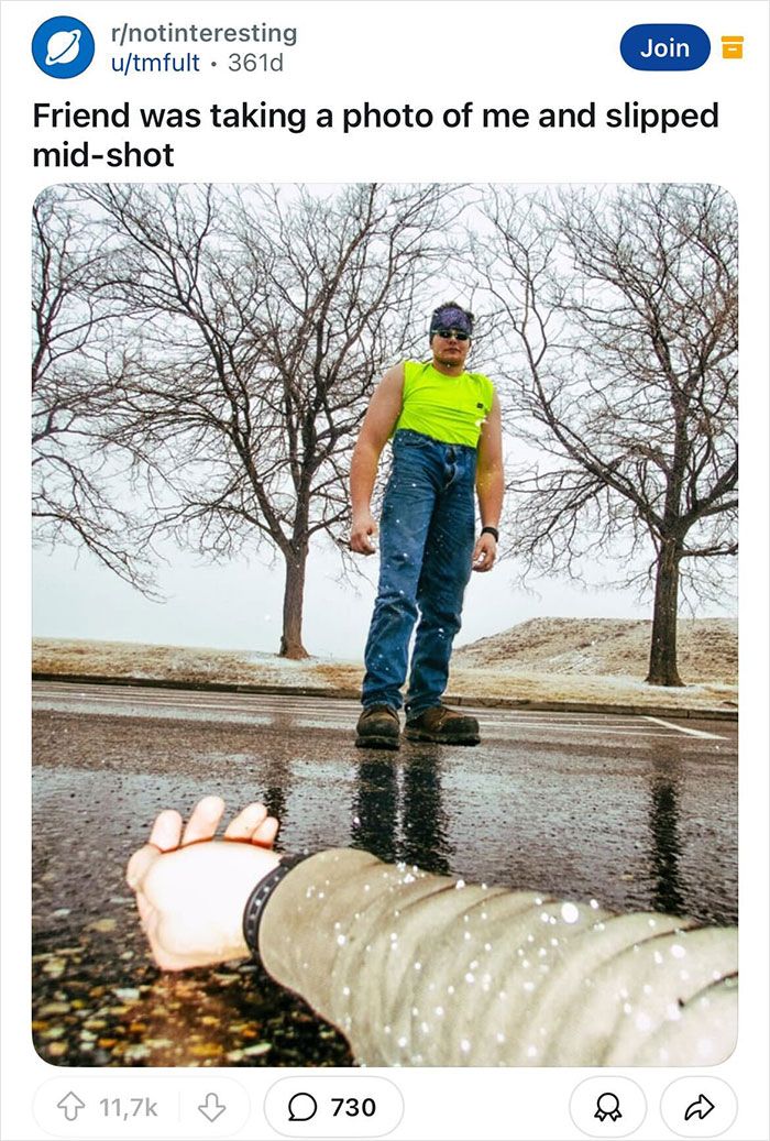 Man in neon tank top appears large as a hand lays on wet ground, creating a unique perspective photo.
