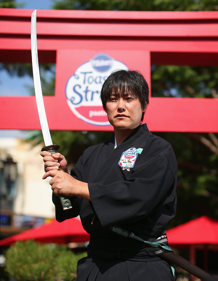 Person demonstrating sword skills in traditional attire, showcasing real-life superpowers in a public setting.