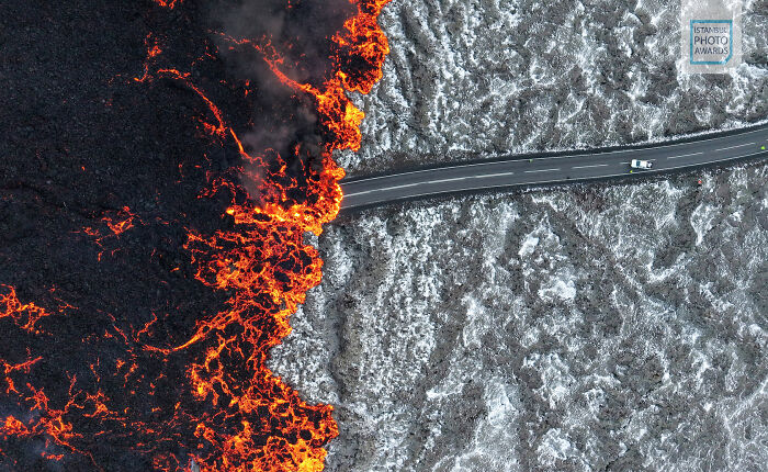Overhead view of a car on a road running through a volcanic landscape, featured in the Istanbul Photo Awards 2025.