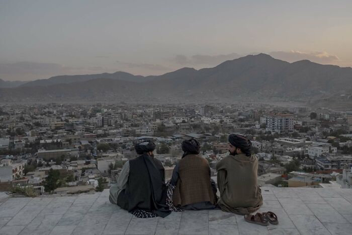 Three people overlooking a cityscape at dusk, mountains in the background, featured in Istanbul Photo Awards 2025.