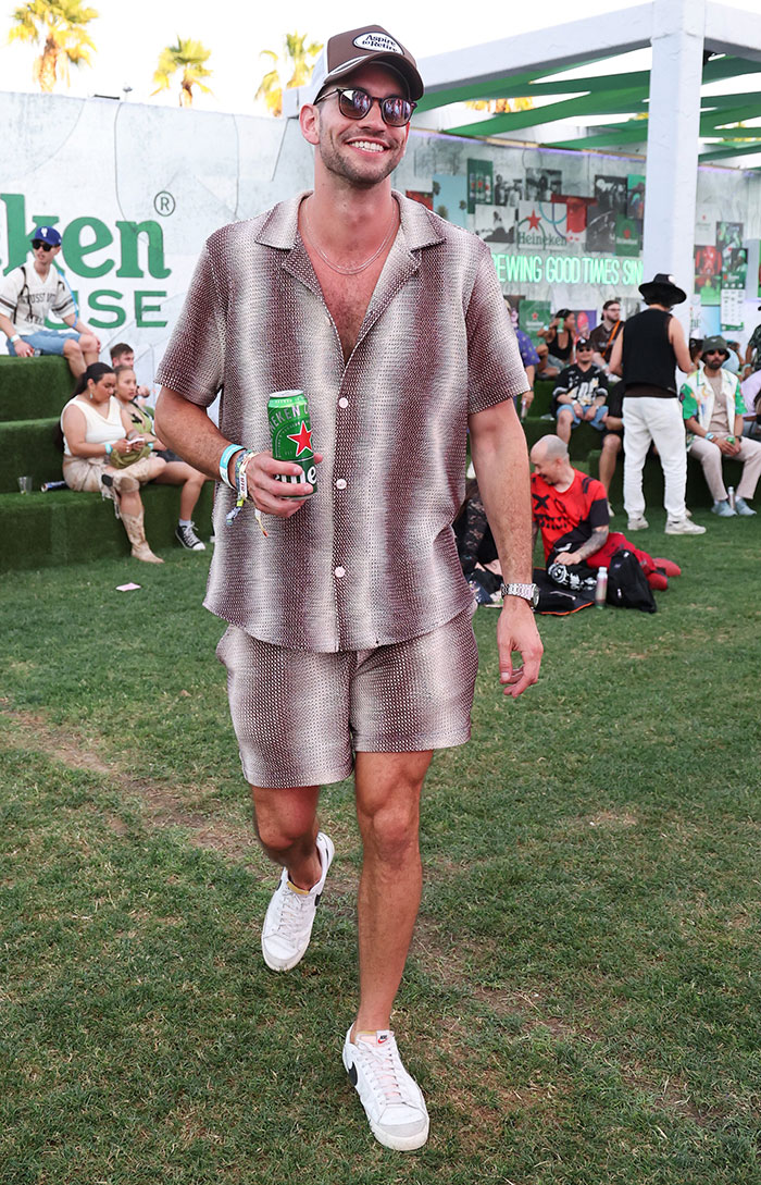 Worst dressed at Coachella 2025, a man in matching casual outfit holding a drink, with sunglasses and a cap.