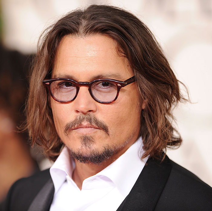 I don't know who this is, but they have shoulder-length hair and glasses, wearing a suit and white shirt, in a formal setting. I don't know who this is, but they have shoulder-length hair and glasses, wearing a suit and white shirt, in a formal setting.