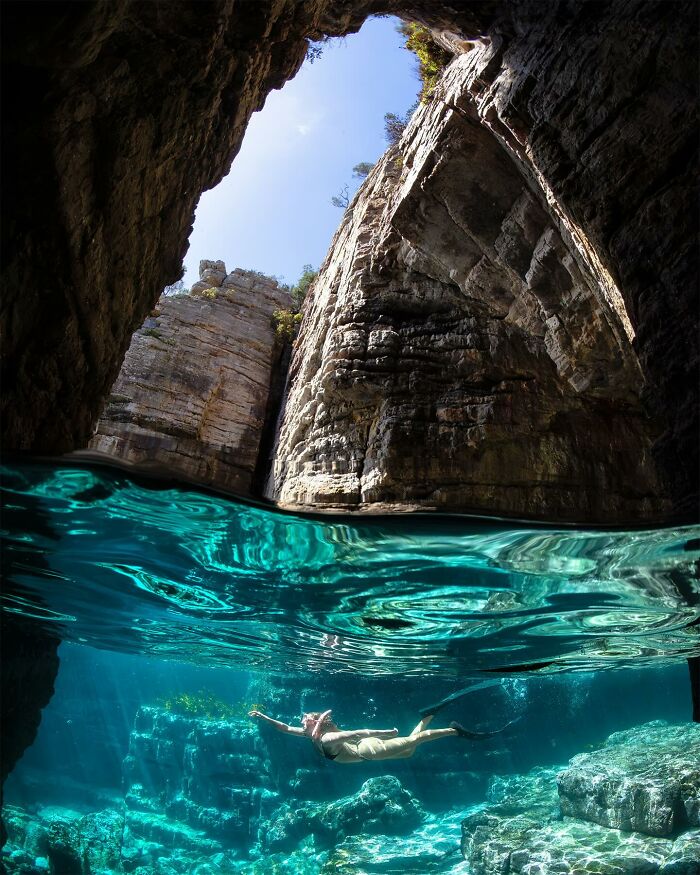 A swimmer explores a stunning underwater cave, capturing the magical world where ocean meets sky.