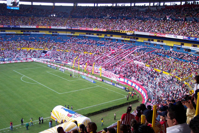 Crowded stadium with football fans, energetic atmosphere, and vibrant team banners.