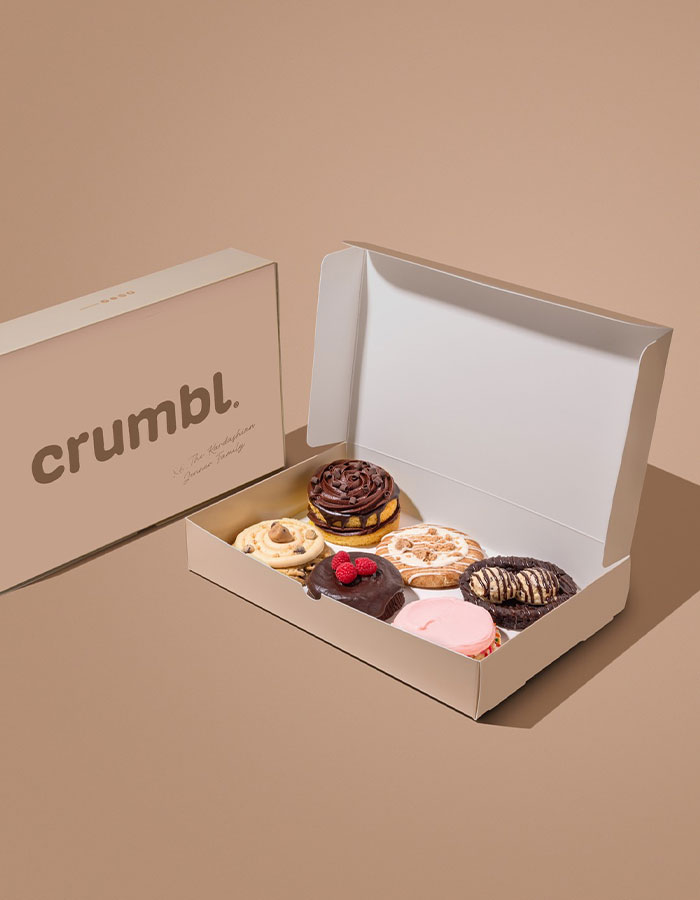 Crumbl's Kardashian-themed cookies in an open box on a beige background. Crumbl's Kardashian-themed cookies in an open box on a beige background.