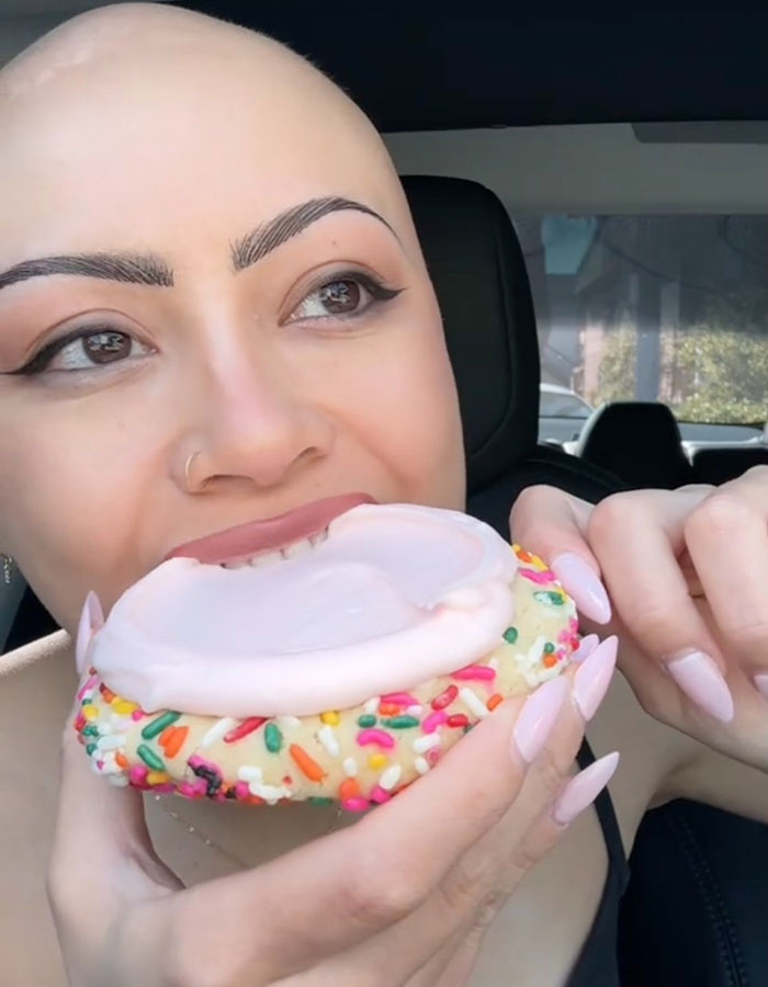 Person enjoying a Crumbl cookie with sprinkles and frosting in a car, highlighting controversy on Kardashian cookies. Person enjoying a Crumbl cookie with sprinkles and frosting in a car, highlighting controversy on Kardashian cookies.