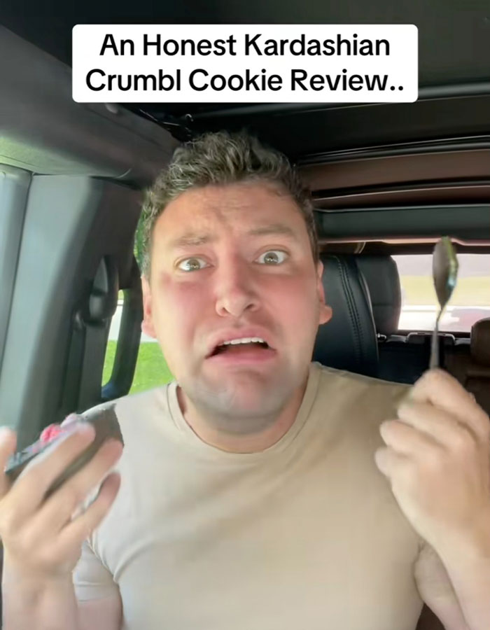 Man in car reacting to new Crumbl Kardashian cookie, holding a spoon and cookie, expressing surprise and concern. Man in car reacting to new Crumbl Kardashian cookie, holding a spoon and cookie, expressing surprise and concern.