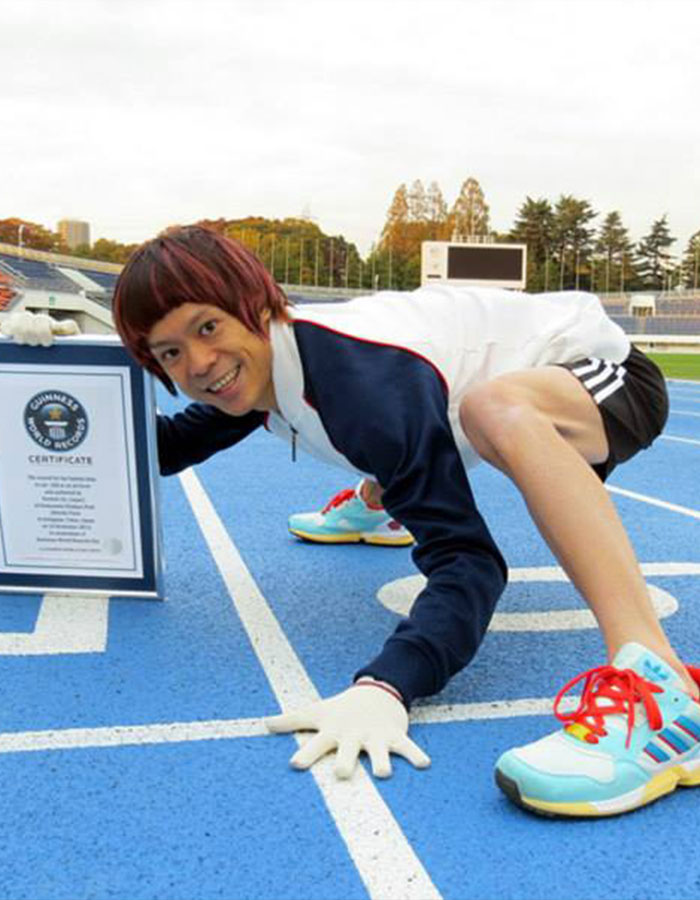 Person on a running track in a crouched pose, holding a Guinness World Records certificate, showcasing real-life superpowers.