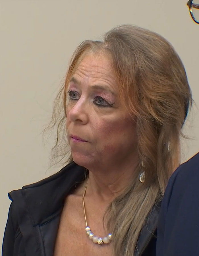 Woman involved in stepson case discusses her perspective, wearing a necklace and dark jacket.