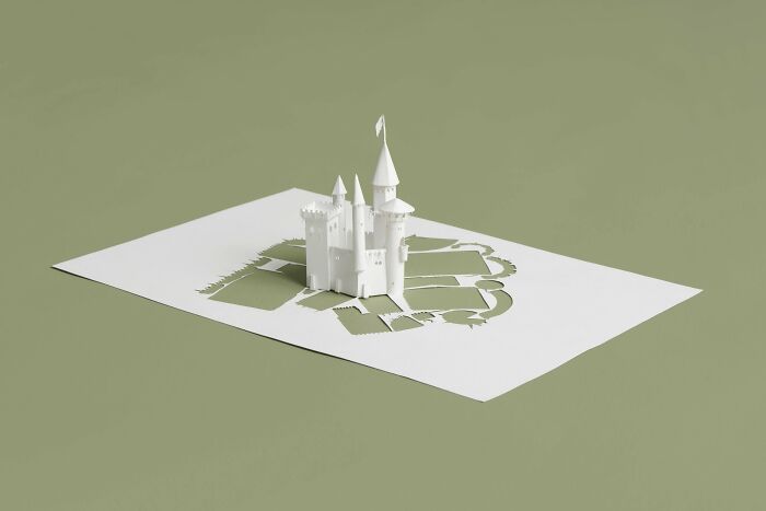 Paper castle miniature by Peter Callesen, intricately crafted from a single white sheet.
