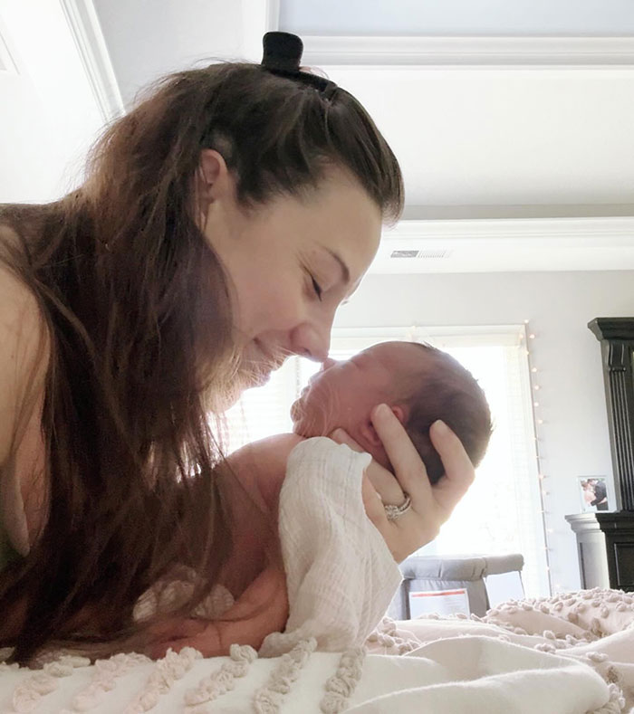 Influencer lovingly cradles her newborn, showcasing a tender moment at home.