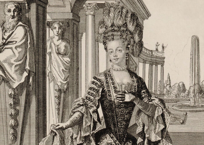 A woman in an elaborate 18th-century gown and hairstyle stands in an ornate architectural setting.