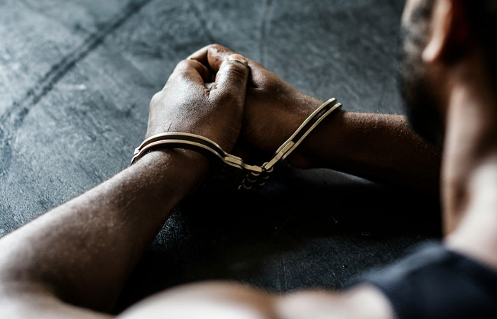 Man with hands tied, symbolizing cruelty.