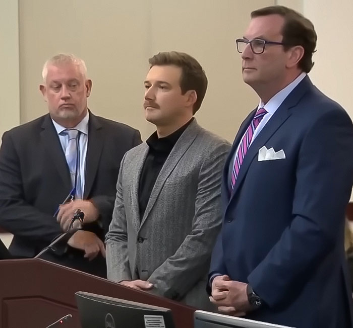 Three men standing together in a formal setting, involved in a discussion about a petulant move.
