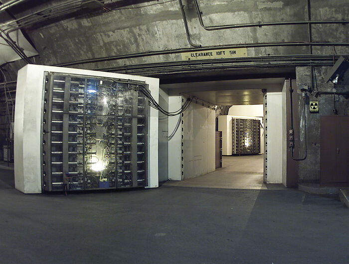 Underground passage with vault doors and exposed cables, resembling eerie cities built below ground.