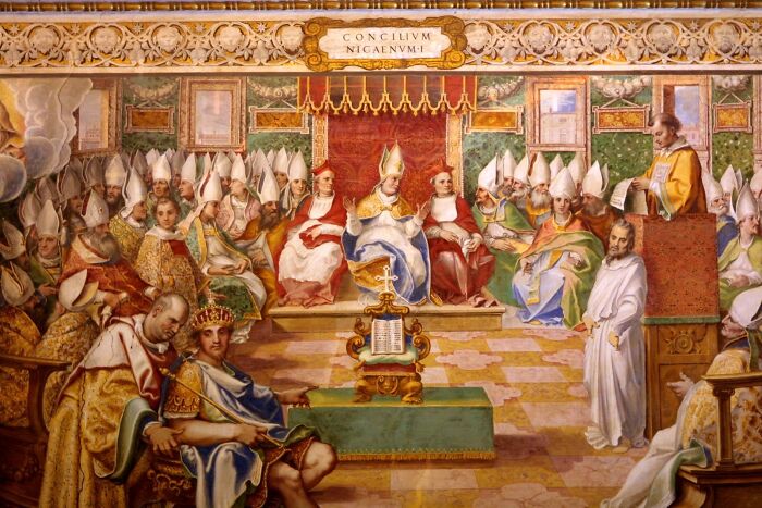 Depiction of a Roman Empire council meeting with bishops and officials in ornate attire, set in a grand hall.